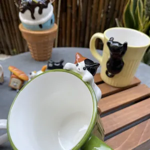 Detailed view of handmade ceramic cat mugs with 3D cat figurines on stone tabletop