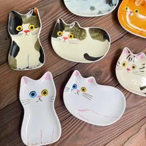 Vista dall'alto di vari piatti per condimenti in ceramica a forma di gatto su legno scuro