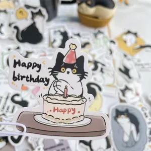 Close-up of a cartoon tuxedo cat sticker with a birthday cake and party hat for DIY