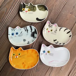 Dettaglio di cinque ciotole per salse in ceramica a forma di gatto su un tavolo di legno