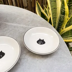 Japanese style cute black cat ceramic sauce dishes on a stone tabletop with bamboo