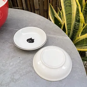 Close-up of ceramic black cat seasoning dishes on a stone table with natural sunlight