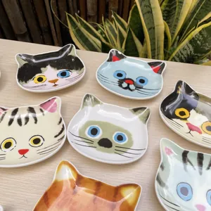 Close-up of cute cat-shaped ceramic sauce dishes with various hand-painted faces