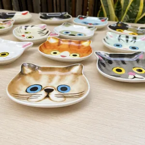 Macro detail of various hand-painted ceramic cat-shaped seasoning dishes on a wood table