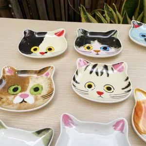 Detailed top view of various cute cat-shaped ceramic sauce dishes on wood surface