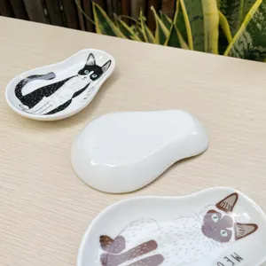 Macro detail of cute cat illustrations and glossy ceramic finish on small soy sauce dishes