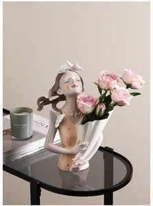 Detail der Mädchen-Vase aus Harz mit Schmetterlingsakzenten und Rosen auf Glastisch