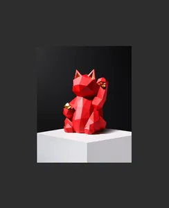 Detail of red geometric lucky cat resin statue with gold accents on a white pedestal