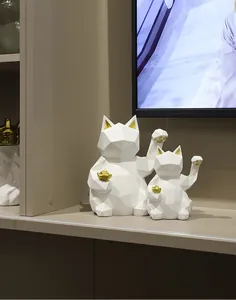 Macro detail of white geometric lucky cat statues with gold foil accents on a shelf