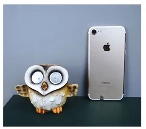 Solar powered owl light side by side with a smartphone to demonstrate product size