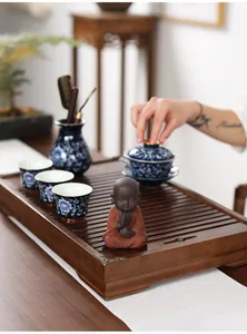 Macro detail of Chinese Zen tea set featuring blue porcelain cups and a purple clay monk