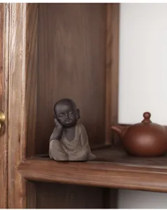Zen style purple sand monk ceramic ornament resting on a wooden display tea stand