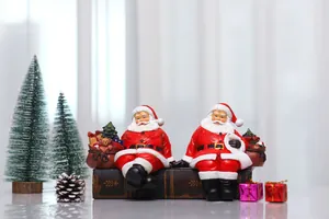 Detail of two resin Santa Claus figurines sitting on vintage book bases with gift bags