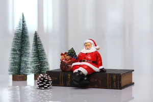 Detail of resin Santa Claus sitting on books with gift bag and mini Christmas trees