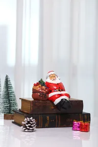 Close-up of sitting Santa Claus figurine with gift bag on vintage books decoration