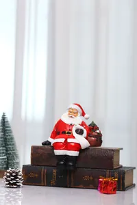Detail of resin Santa Claus sitting on vintage books with a gift bag and white scroll