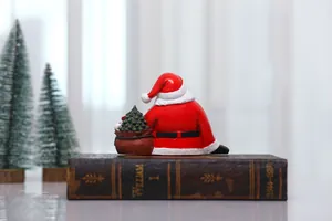 Detail of Santa Claus resin figurine sitting on vintage books with a gift bag