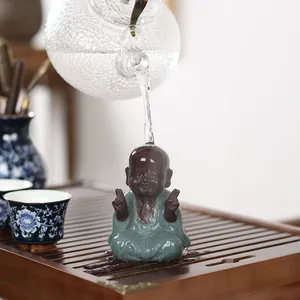 Ceramic little monk tea pet figurine on wooden tray with hot water flowing over it