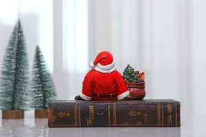 Detailed view of resin Santa Claus sitting with gift bag on vintage books for decor