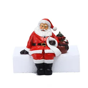Detail of resin Santa Claus figurine with white scroll and a brown gift bag with a tree