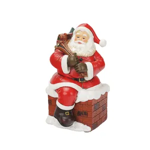 Statuina tradizionale di Babbo Natale in resina seduto su un camino con regali
