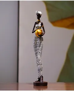 Détail d'une figurine de femme africaine tenant un vase doré aux motifs géométriques