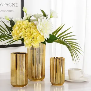 Three-piece set of modern gold ceramic vases with vertical texture and floral arrangement