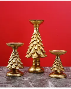 Close-up of three golden Christmas tree candle holders with textured pine branch details