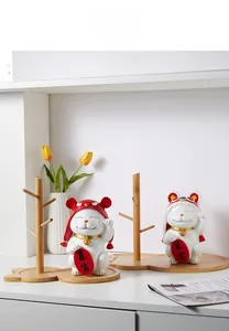 Detail of lucky cat ceramic statues with wooden branch stand for home decor