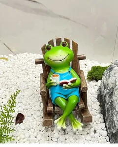 Grenouille drôle en salopette bleue lisant et buvant du café sur un fauteuil à bascule