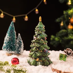Miniatuur kerstboom van hars met gouden ster en decoraties op sneeuw achtergrond