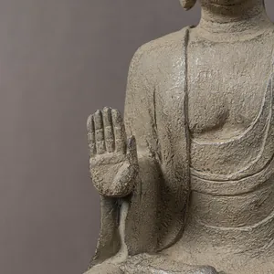 Detail of sandstone resin Buddha statue showing Fearless Mudra hand and textured robe