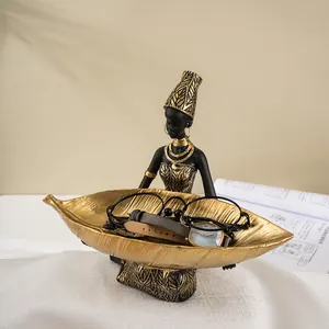 Λεπτομέρεια αφρικανικής φιγούρας με χρυσό δίσκο φύλλων για αποθήκευση ρολογιών και γυαλιών