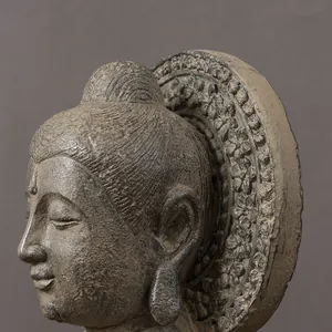 Detailed close-up of a carved Buddha head with intricate floral relief on a stone-like halo