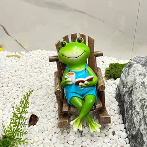 Figurine de grenouille sur chaise basculante en résine lisant un livre bleu