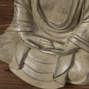 Close-up of resin Buddha statue showing fine hand details and antique weathered texture