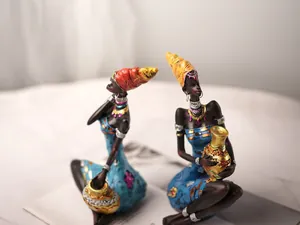 Detail of two resin African tribal figurines in vibrant blue robes holding golden jars