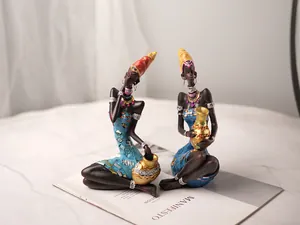 Detailed close-up of African resin figurines with blue dresses and gold sequin accents