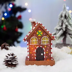 Detailed LED resin gingerbread house ornament with candy cane roof on snowy base