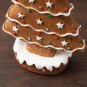 Close-up of gingerbread Christmas tree figurine with frosting detail on wood surface