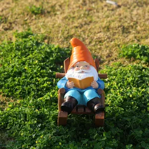 Garden gnome figurine reading on a wooden style rocking chair placed on green lawn