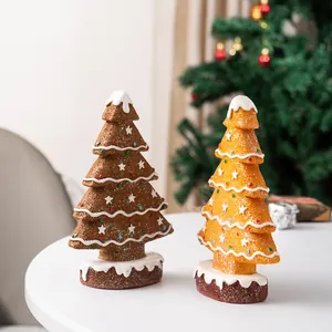 Close-up of two gingerbread Christmas tree resin ornaments with snowy tops and glitter