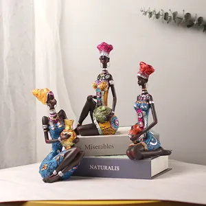 Three-piece set of African resin figurines with colorful attire and glitter on books