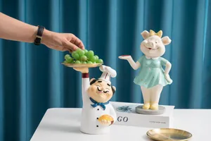 Détail de statues en résine de chef et cochon tenant des plateaux dorés avec fruits