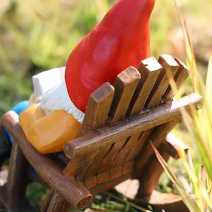 Detailed close-up of a resin garden gnome figurine reading a book on a rocking chair