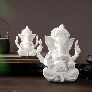 Macro detail of white resin Ganesha statues showing intricate carvings and Om religious symbols