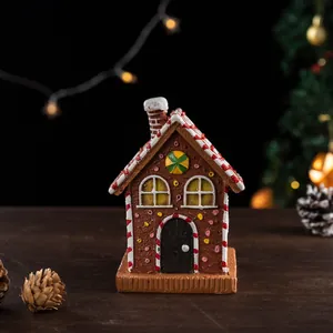 Close-up of resin gingerbread house ornament with snowy eaves and festive holiday details