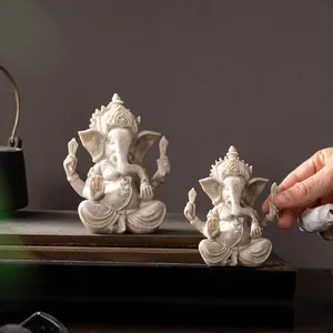 Detailed comparison of two Ganesha resin statues in different sizes on wooden base