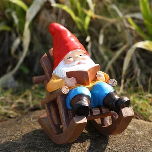 Detailed garden gnome figurine sitting on a rocking chair reading a book in grass