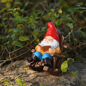 Detailed view of a garden gnome sitting in a rocking chair reading a book garden decor